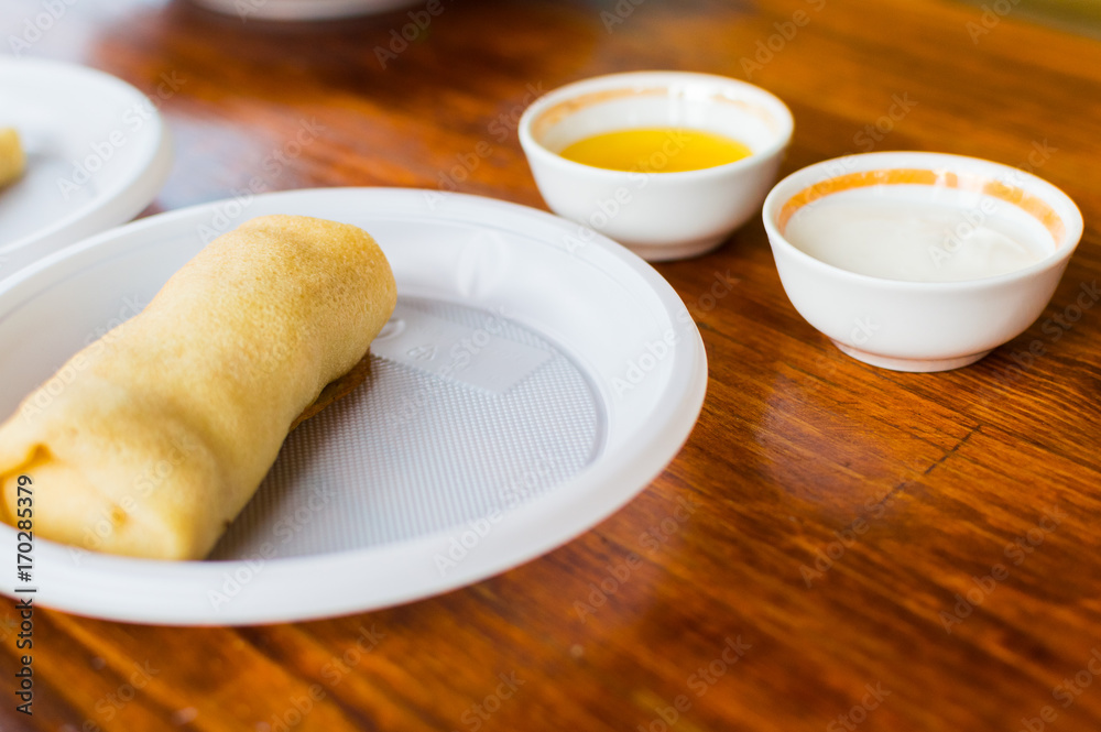 Pancake on a plastic plate. Honey and sour cream in the background Pancake on a plastic plate. Honey and sour cream in the background
