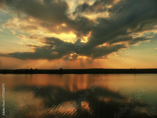 Sunset at lake, storm clouds reflected on the surface of the water photo