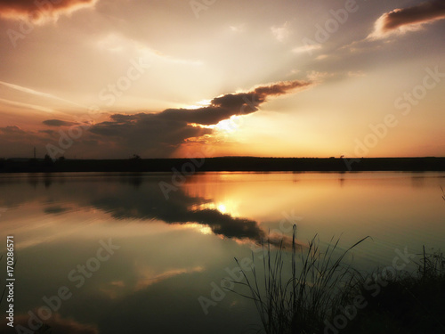 Sunset at lake, storm clouds reflected on the surface of the water