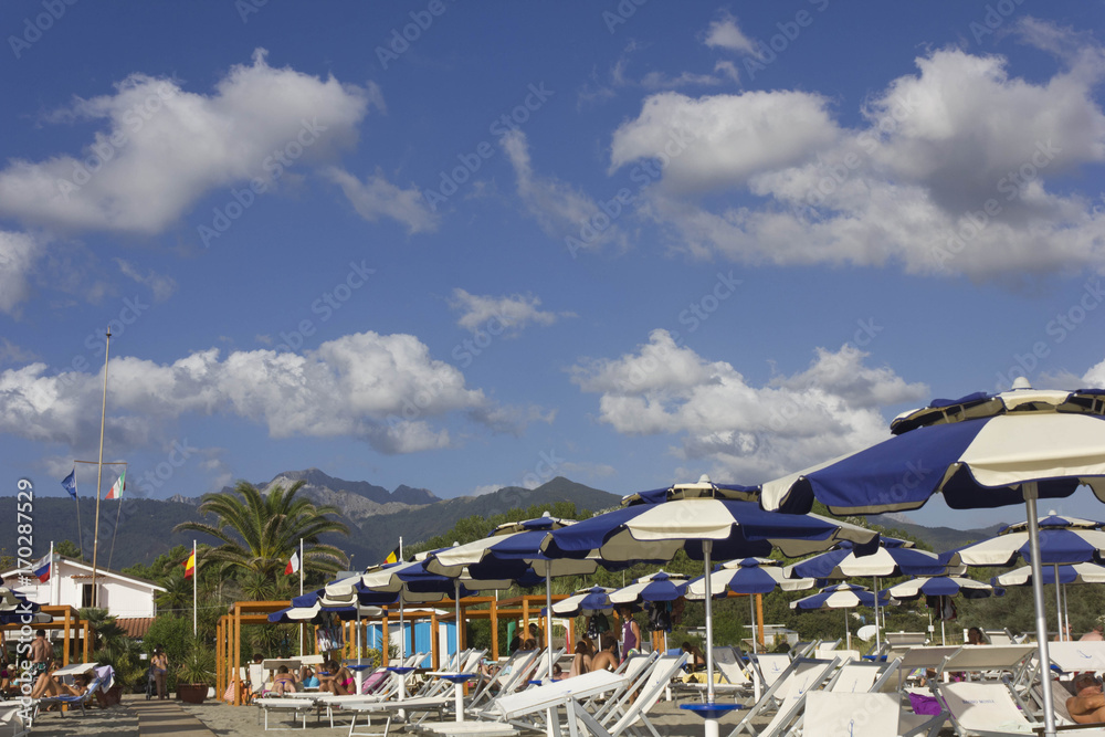 Sun umbrellas on Marina di Massa beach in Tuscany, overlooking the Apuan Alps