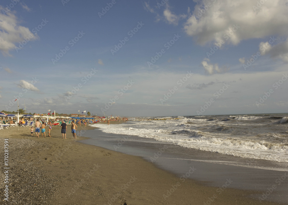 Versilia coastline at day time in summer season, with people around the bathing establishment in a rough seas day