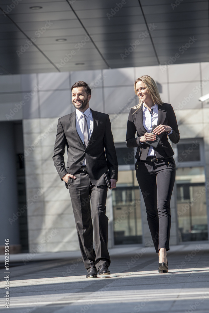 Business partners walking against office building Business partners walking against office building