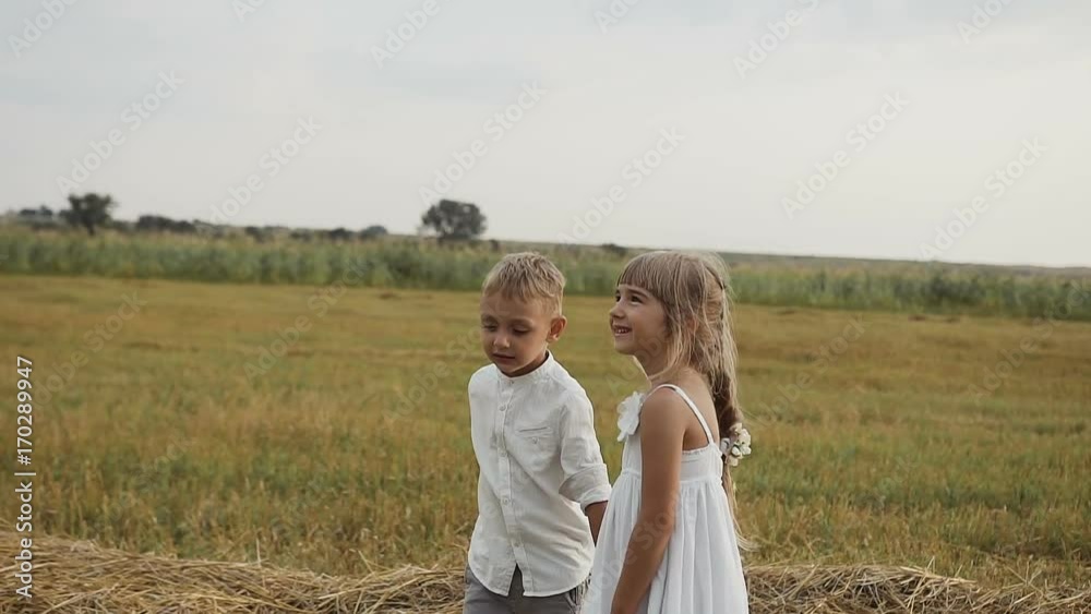 A little boy with a girl standing in the field after the rain and looking into the sky A little boy with a girl standing in the field after the rain and looking into the sky