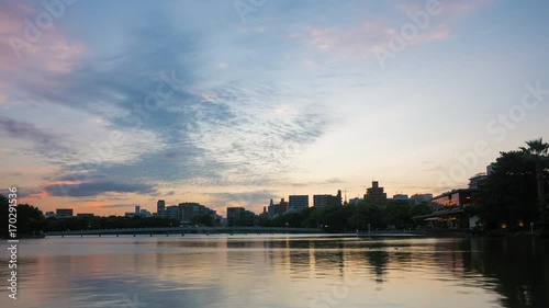 Time lapse of cloudscape reflected on rippled water lake in sunset
