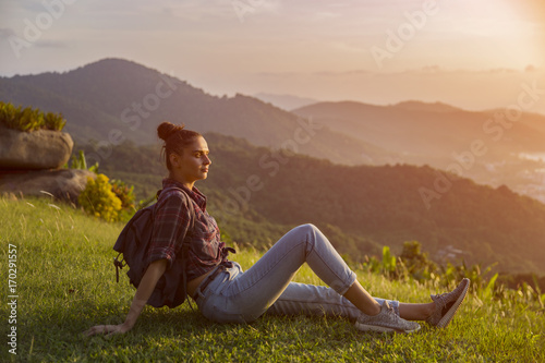 Hipster young girl with backpack enjoying sunset on peak mountain. Tourist traveler on background valley landscape view mockup. Toned. Instagram filter