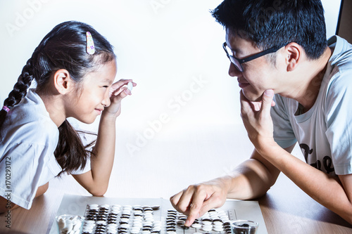 Father and daughter playing Go board game, Concept of strategic thinking or planning photo