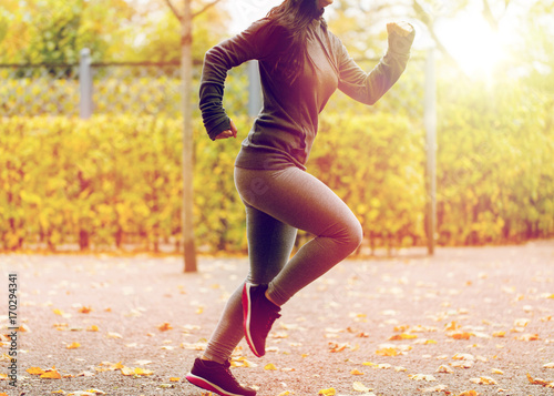 close up of young woman running in autumn park