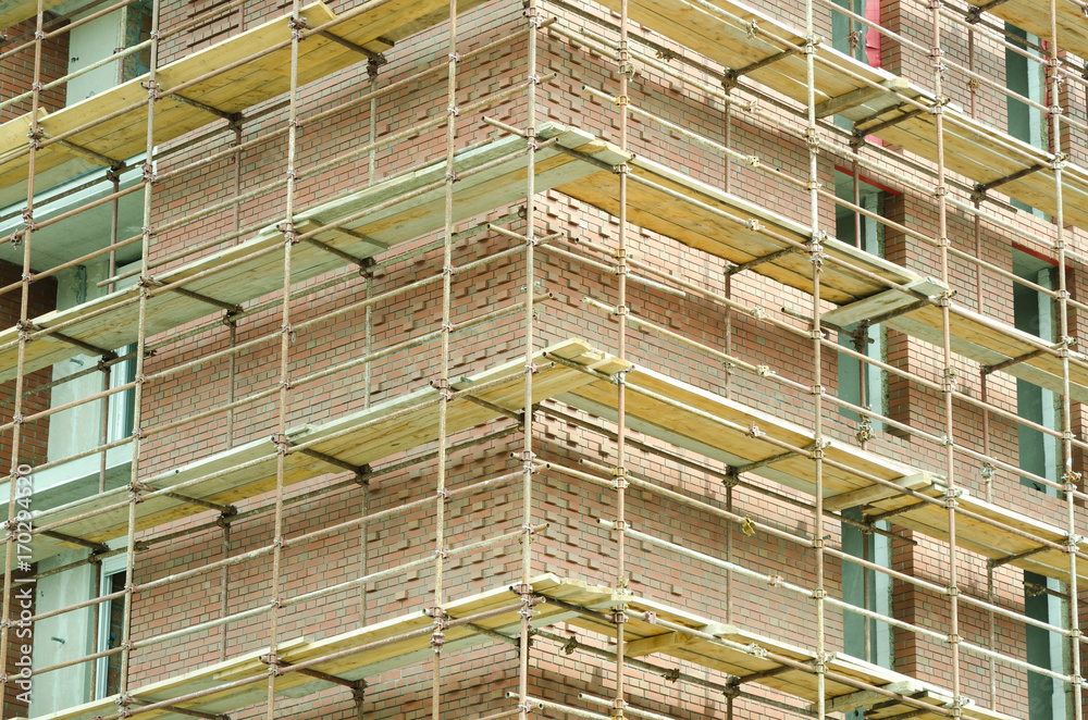 Corner of red brick building construction site with scaffolding