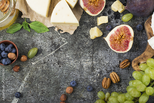 Cheese board for snacks, tricks, meetings with friends, on a gray stone background: assorted cheeses, young cheese, parmesan, cheese with fenugreek, figs, nuts, honey, grapes. Top View. photo