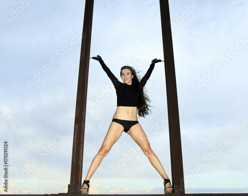 Young girl posing on the rusty structures over blue sky