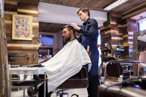man and barber styling hair at barbershop
