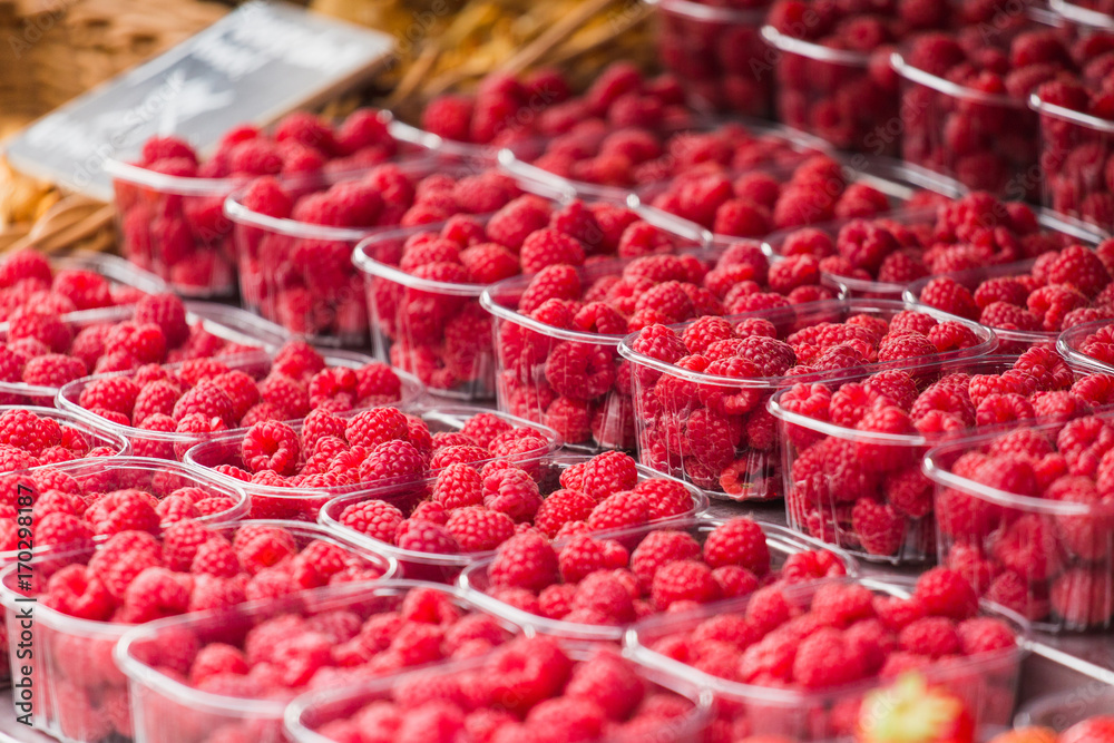 A lot of raspberries on the street market counter.
