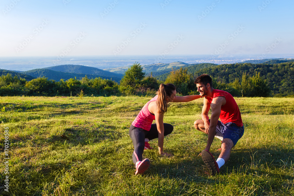 Young couple stretching their muscle in nature before running. Young couple stretching their muscle in nature before running.