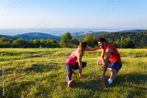 Young couple stretching their muscle in nature before running.