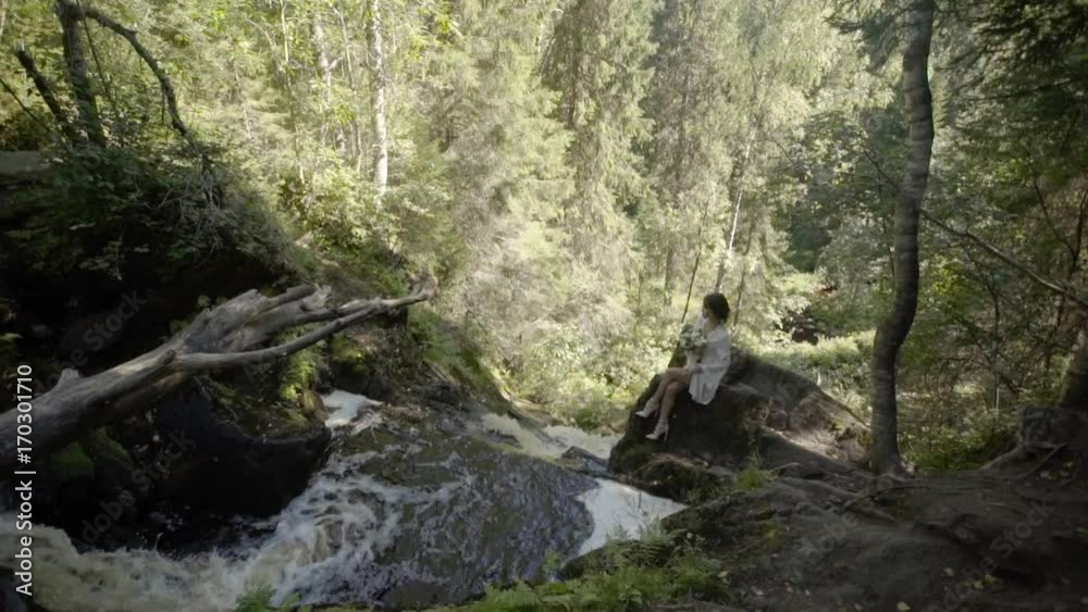 Young woman sitting on a rock near waterfall in lingerie Young woman sitting on a rock near waterfall in lingerie