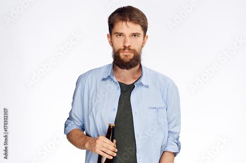 1410446 A man in a blue shirt and a black T-shirt is holding a bottle of beer