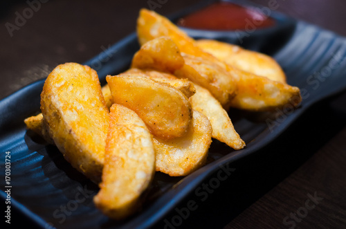 sweet potato fries with ketchup on black plate over old wooden table.