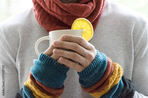 A young man holding a Cup of tea and lemon. Cold, cold, disease.