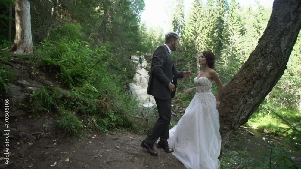 Young couple embracing near waterfall slowmotion Young couple embracing near waterfall slowmotion