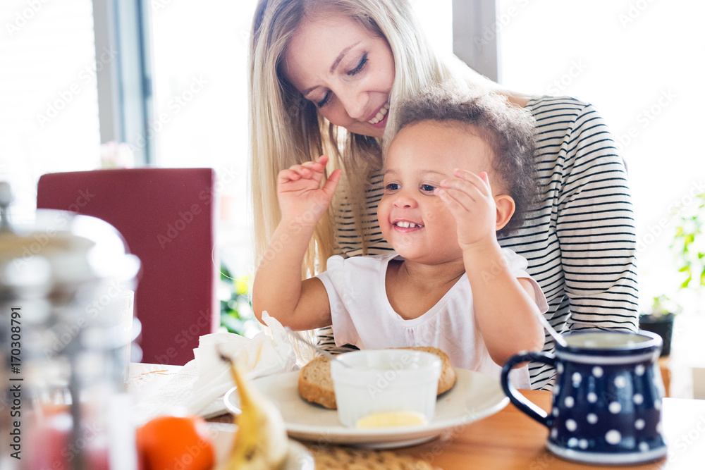 Beautiful young mother with his daughter having breakfast.