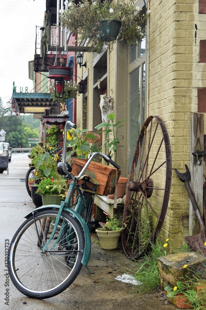 Two wheels on sidewalk of small town on a rainy day