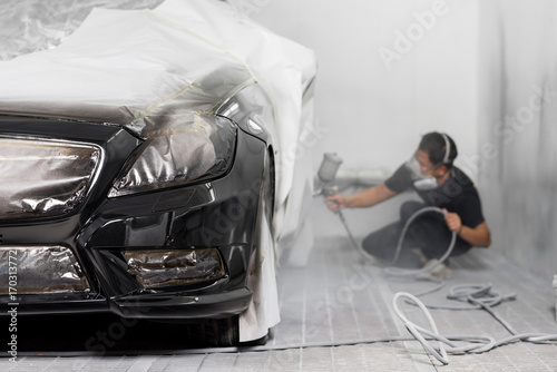 Auto body repair series: Black car being paint in paint booth