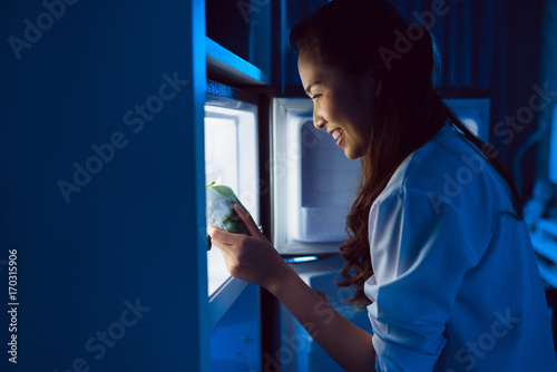 Asian women open the refrigerator, eat dessert at night.
