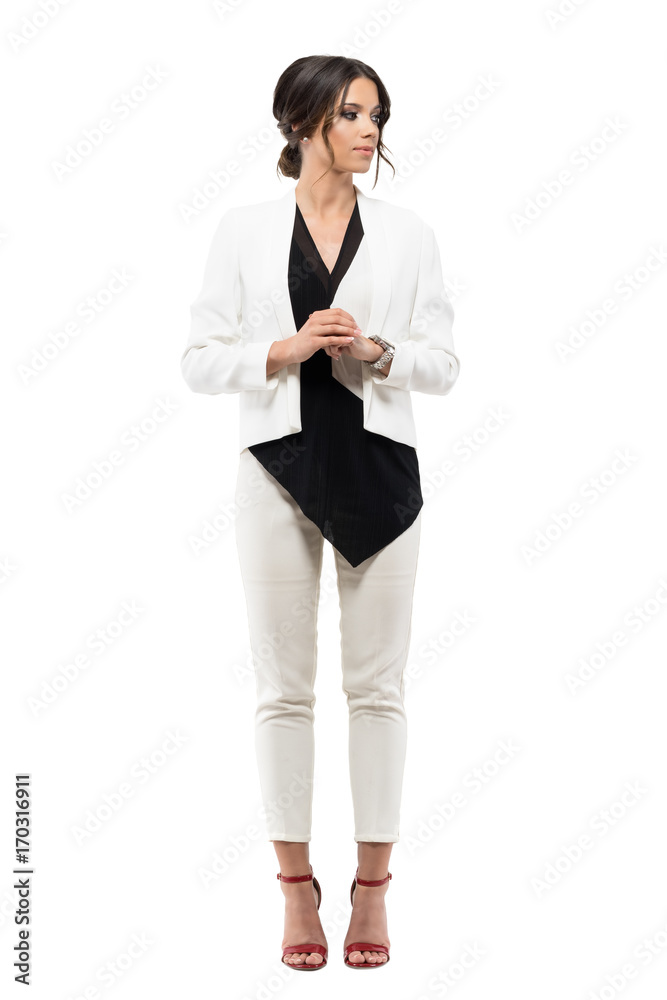 Elegant business woman in suit standing in formal posture with hands clasped looking away. Full body length portrait isolated on white background Elegant business woman in suit standing in formal posture with hands clasped looking away. Full body length portrait isolated on white background