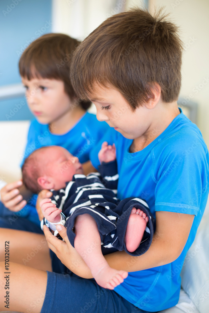 Two boys, brothers, meeting for the first time their new baby brother at hospital Two boys, brothers, meeting for the first time their new baby brother at hospital