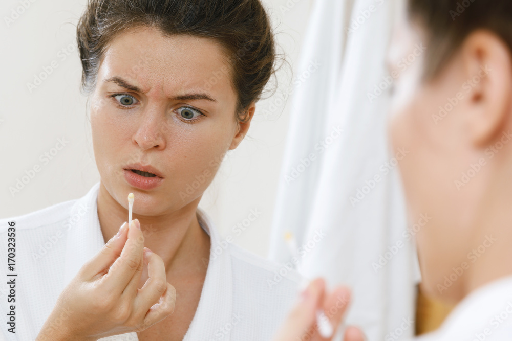 Woman cleansing her ears with a cotton swab Woman cleansing her ears with a cotton swab