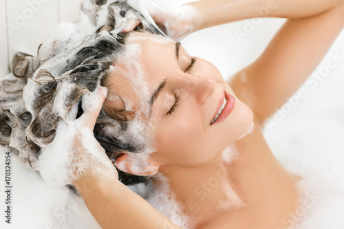 Woman is washing her hair with shampoo photo