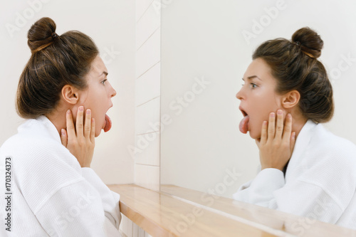 Foto Woman looking on her tongue in the mirror