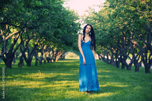 Brunette woman posing among rows of apple trees