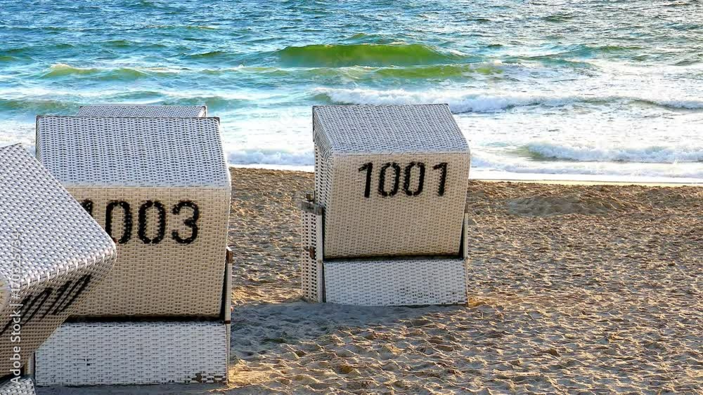 Weisse Strandkörbe vor ruhiger Nord See im warmen Sonnenuntergang Licht