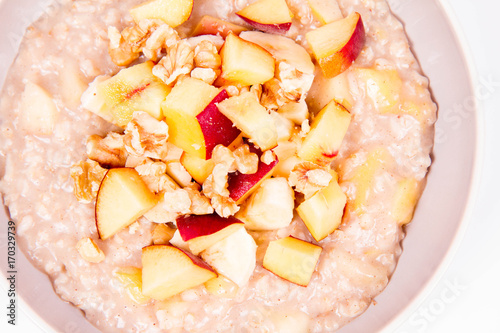 Porridge with peach, apple, banana and walnut on a white background photo