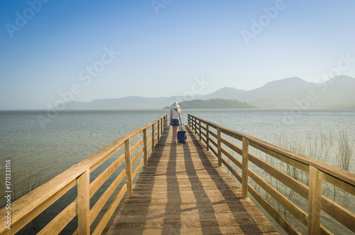 Ótimo conceito de viajar, férias, mulher caminhando com bagagem em doca, esperando o navio para viajar.