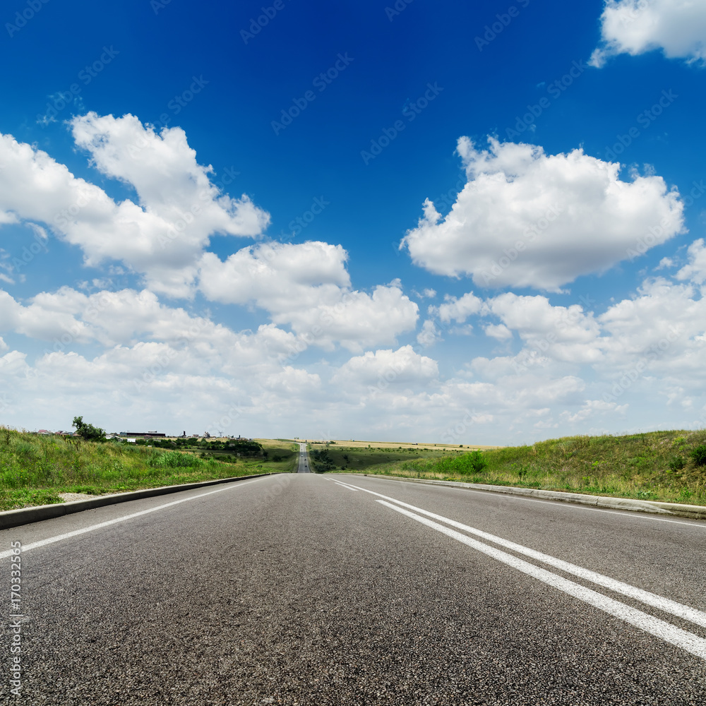 asphalt road to horizon and deep blue sky with white clouds