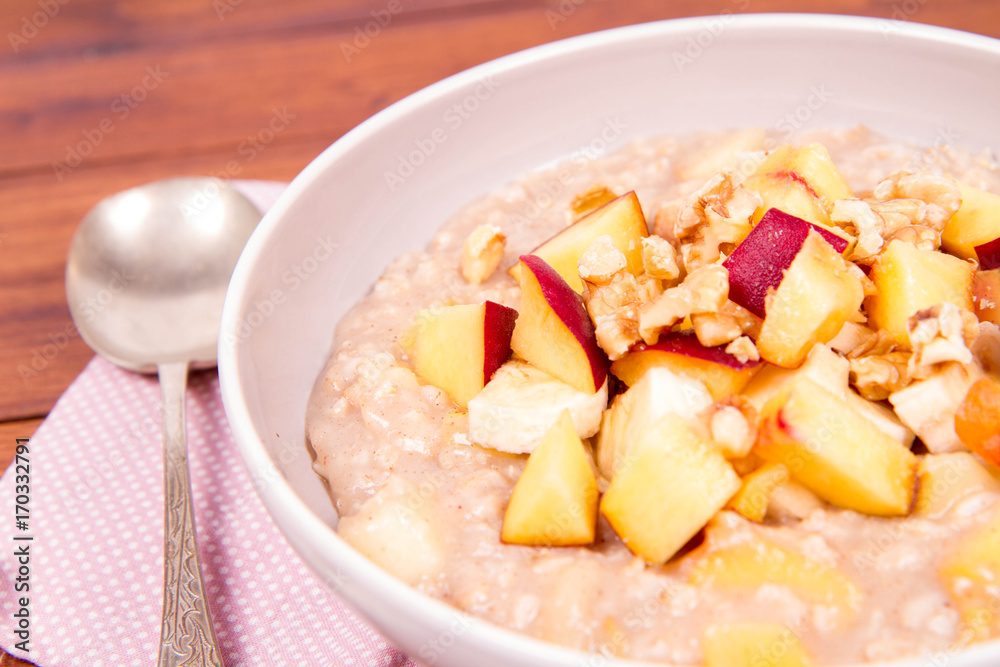 Porridge with peach, apple, banana and walnut on a wooden table Porridge with peach, apple, banana and walnut on a wooden table