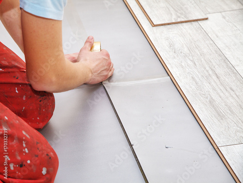 Fotografija handyman's hands laying down laminate flooring boards