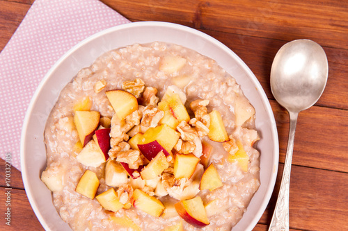 Porridge with peach, apple, banana and walnut on a wooden table photo