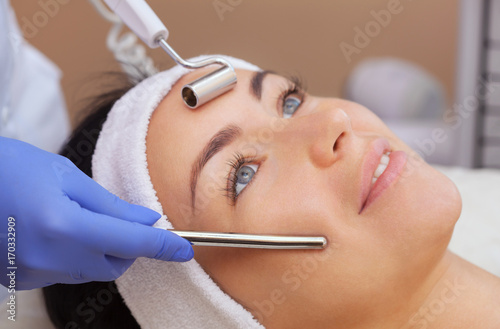 The cosmetologist makes the apparatus a procedure of Microcurrent therapy of a beautiful, young woman in a beauty salon. Cosmetology and professional skin care. photo