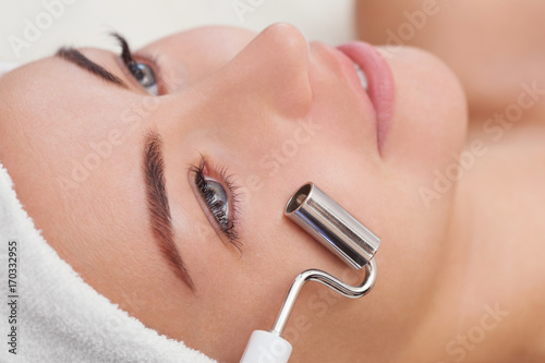 Tablou pe pânză The cosmetologist makes the apparatus a procedure of Microcurrent therapy of a beautiful, young woman in a beauty salon
