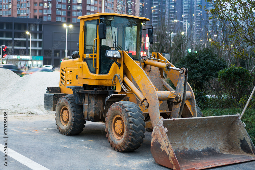 Old yellow bulldozer with caterpillar moving ground with scoop. Blue sky and white clouds in background Old yellow bulldozer with caterpillar moving ground with scoop. Blue sky and white clouds in background