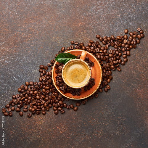 Coffee beans with cup of cofee on brown concrete table with copy space for design.