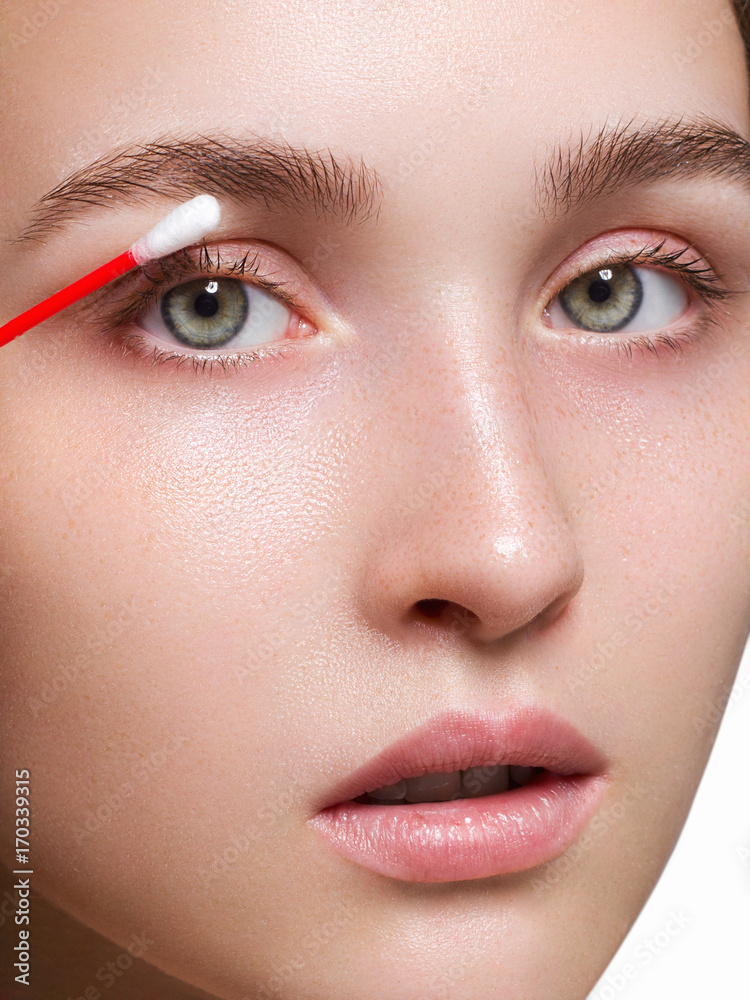 Care of skin the woman deletes cosmetics from a face with a Qtip