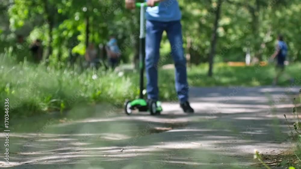 Boy riding mini scooter, kick scooter in the park in slow motion. 1920x1080 Boy riding mini scooter, kick scooter in the park in slow motion. 1920x1080