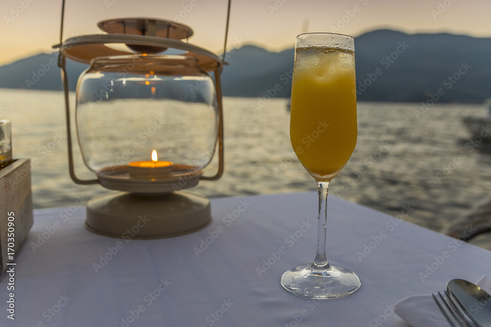 Obraz premium фужер с коктейлем на фоне заката на набережной 
