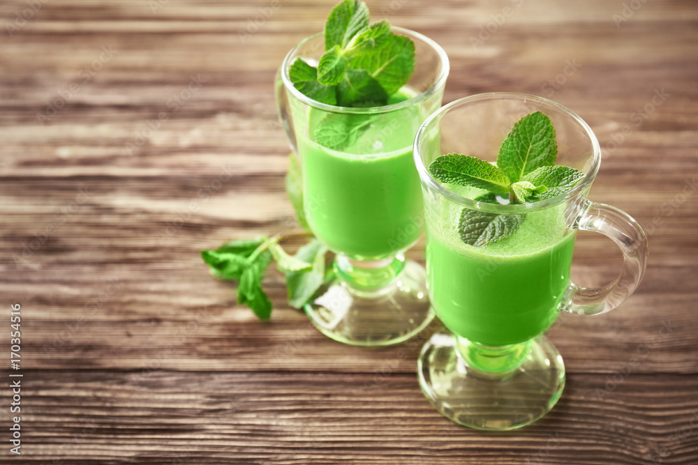 Glasses of green healthy juice with mint on wooden table Glasses of green healthy juice with mint on wooden table
