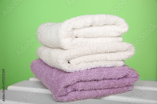 Clean towels on table against color background