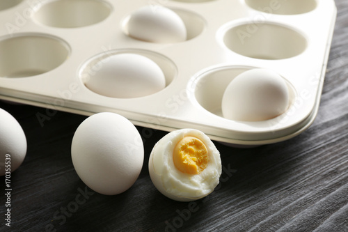 Muffin tin and hard boiled eggs on wooden table